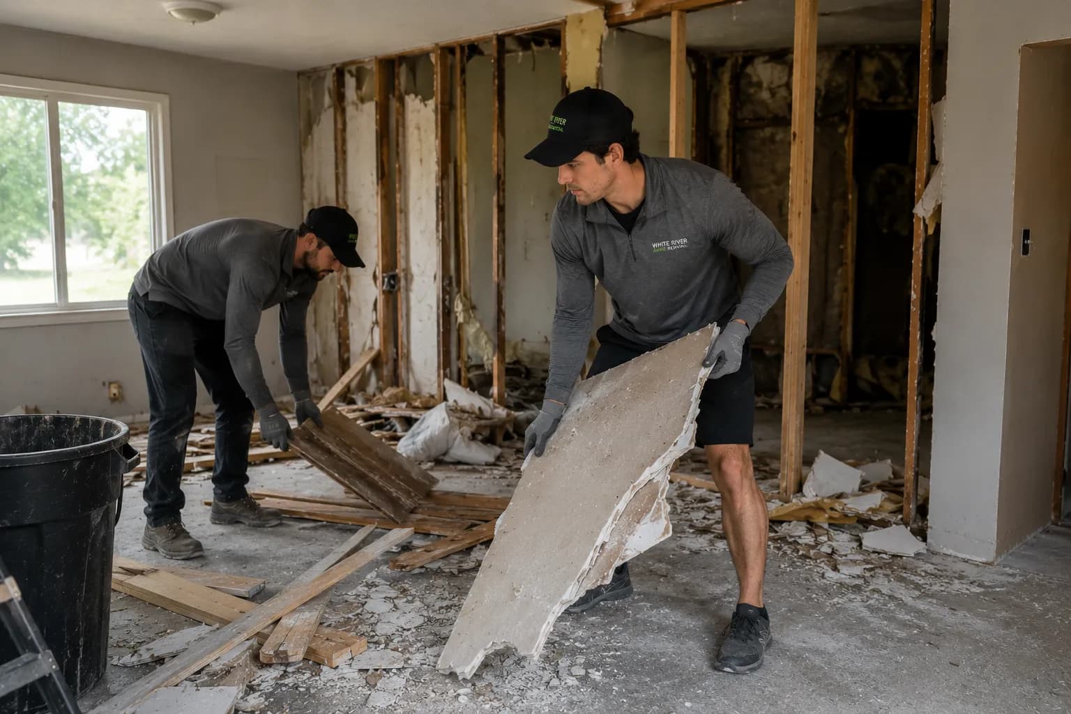 Crew members clearing drywall and building debris from a renovation project